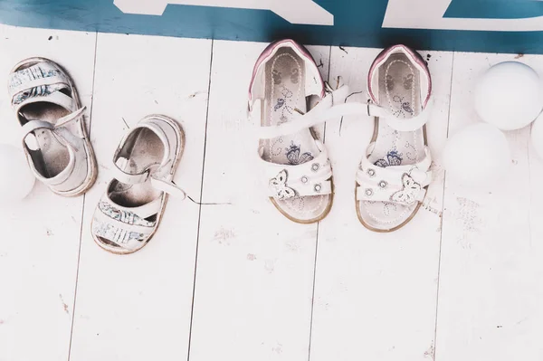White open-toe kids sandals on a wooden floor