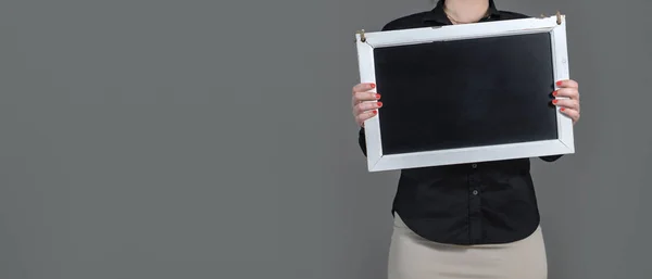 Mujer sosteniendo pizarra con espacio para copiar. Un montón de espacio en blanco gratuito para texto y contenido. Fondo gris oscuro . — Foto de Stock