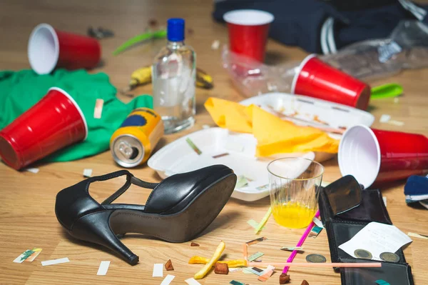 Uma confusão terrível depois da festa. Lixo, garrafas, alimentos, copos e roupas no chão . — Fotografia de Stock