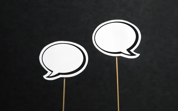 2 blank speech bubbles on a dark black background. Chat bubble cut from paper with wooden stick. — Stock Photo, Image