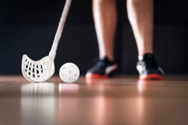 Beyaz top ve sopayla duran florbol oyuncusu. Yer hokeyi konsepti.