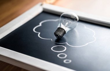 Fikri mülkiyet, yeni fikir, psikoloji veya beyin fırtınası konsepti. Yaratıcılık, yenilik ve ilham. Enerji tüketimi. Tahtada düşünce baloncuklu ampul.