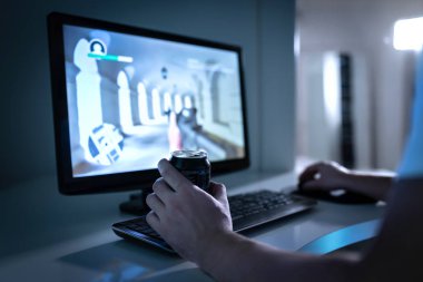 Oyuncu adam video oyunu oynuyor ve konserve soda ya da enerji içeceği içiyor. Bilgisayar monitöründe Fps video oyunu. Gece geç saatlerde kumar bağımlısı. İnternette birinci şahıs nişancılara bağımlı genç bir adam..