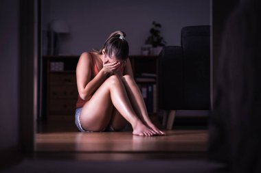 Cinsel taciz, aile içi şiddet ya da taciz kurbanı. Genç üzgün kadın ağlıyor ve evde yerde oturuyor. Utangaç, korkmuş ya da duygusal acı çeken yalnız bir kadın. Stres, travma ya da üzüntü.