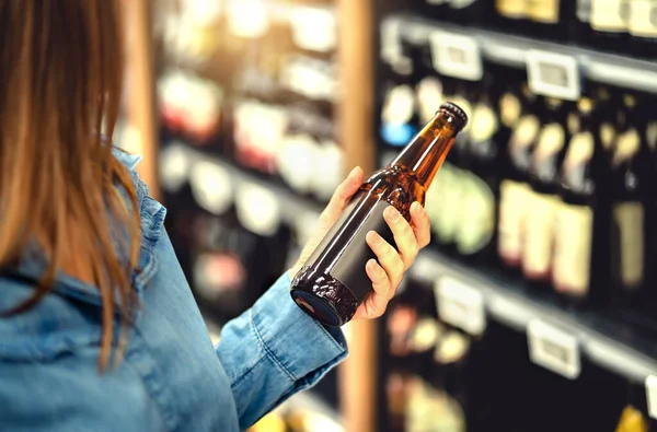 顾客在酒铺买啤酒 手工啤酒或麦芽啤酒 Ipa或淡淡的啤酒 酒柜里的女人超市里的饮料段和过道 女士手里拿着瓶子 饮酒业概念 — 图库照片