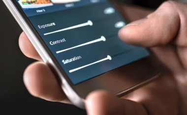 Cep telefonu ve akıllı uygulama ile fotoğraf düzenleme. Sürgüleri ayarlayan adam. Resim düzenleme, manipülasyon, akıllı telefonla geliştirme veya geliştirme. Sosyal medya uygulamasında fotoğrafa filtre ekleniyor.