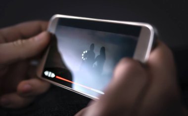 Yavaş internet, video yükleme ve indirme hızı. İnternette film izliyorum. Simge ekrana yükleniyor. Sinirli ve kötü yayın bağlantısı olan sinirli bir insan. Cep telefonu olan adam..