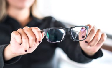 Woman holding new glasses. Lenses and spectacles getting fix and repair by professional optician. Optometrist, oculist or eye doctor in clinic. Bifocal or multifocal specs. Optometry, sight and vision clipart