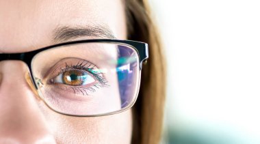 Close up of eye and woman wearing glasses. Optometry, myopia or laser surgery concept. Brown eyed girl with spectacles and eyeglasses. Macro portrait of face and specs. Light reflection on lens. clipart