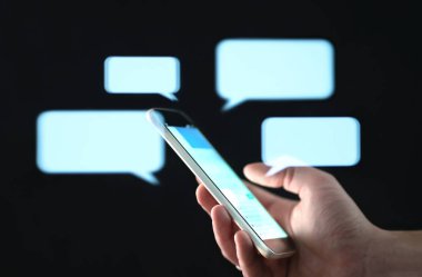 Cep telefonu ekranında soyut hologram konuşma baloncukları olan kısa mesajlar. Anında mesaj yazma uygulaması. Mesajlaşma, grup sohbeti, mesajlaşma ya da kısa mesaj konsepti. Müşteri hizmetleri yardım masasına canlı destek sohbet robotu ile yardım ediyor.