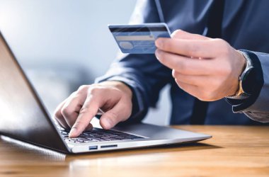 Güvenli online ödeme ve elektronik para transferi güvenliği. Dijital teknolojiyle öde. İnternet bankasına girmek için kredi kartı ve dizüstü bilgisayar kullanan bir adam. Dolandırıcılık, tehdit ve dolandırıcılığı önlemek için mali güvenlik.
