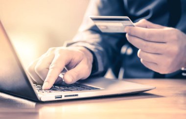 Adam kredi kartı ve dizüstü bilgisayarla online ödeme yapıyor. Dijital e-ticaret servisi. Müşteri alışverişinde ve internette bilgisayarla ödeme yaparken mutlu. Para transferi ve mobil bankacılık kavramı.