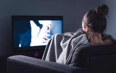 Televizyondaki korku filmi. Geceleri kanepede battaniyenin altında saklanan korkmuş kadın. TV 'de uykusuz insan dizisi ya da film seyrediyor. Karanlıkta yalnız ve korku dolu.