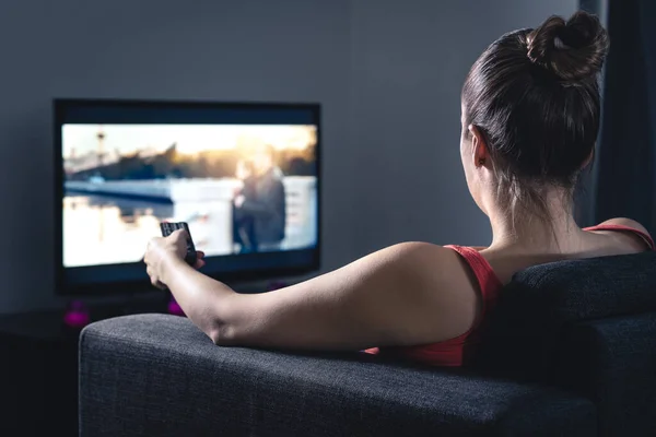 女人在看电影或电视剧 使用智能电视遥控装置选择电影或改变频道的人 电视屏幕上的流媒体或视频点播服务 数码娱乐 — 图库照片