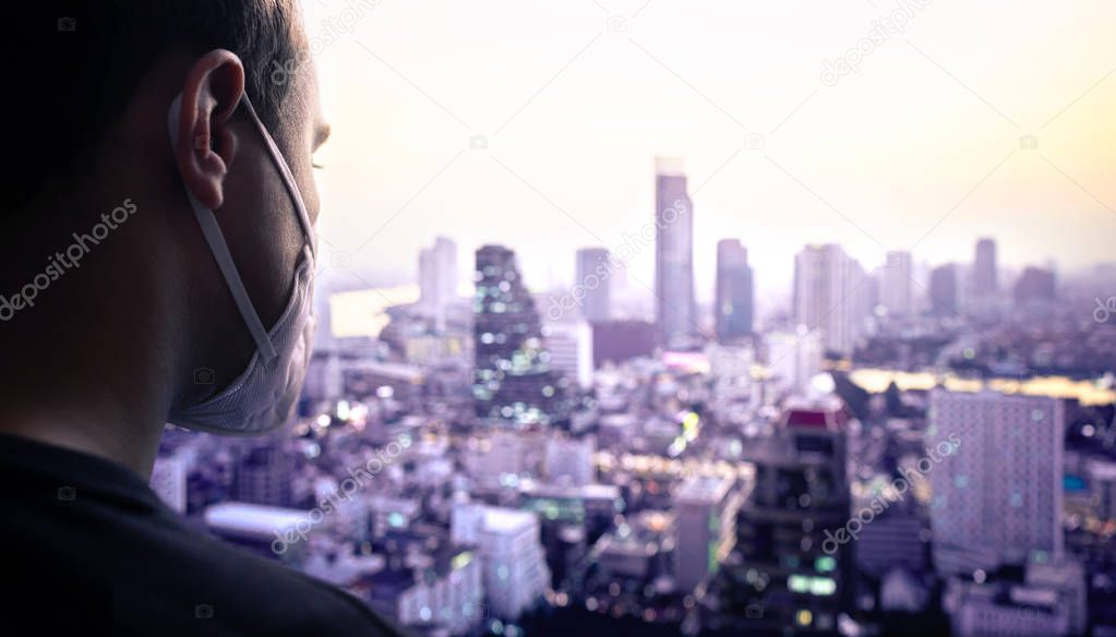 Man wearing a mask in city to protect from pollution or influenza infection. Coronavirus or smog concept. Polluted bad air quality in Asia. Protection from virus with facemask. Urban view from rooftop