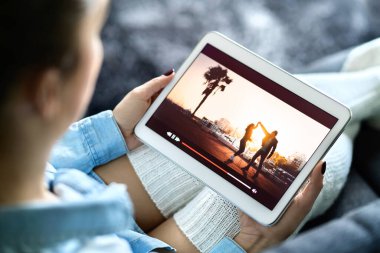 İnternet üzerinden yayın yapan bir film izliyorum. Kadın televizyon dizisi ve film eğlencesi evde rahat bir tabletle yayınlanıyor. Talep üzerine video, VOD. Dijital akıllı aygıt ekranındaki televizyon.