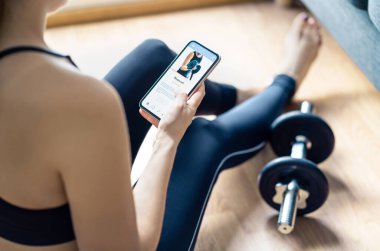 Telefondaki uygulamayla evde spor yapıyorum. Formda bir kadın eğitim videosu izliyor ya da akıllı telefonlu dijital antrenör kullanıyor. İnternet koçu. Spor programı ya da cep telefonundaki sınıf.