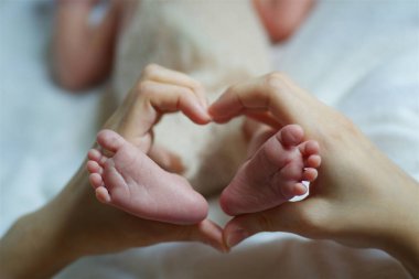 Annenin eli yeni doğmuş bebeğinin bacaklarını tutuyor..