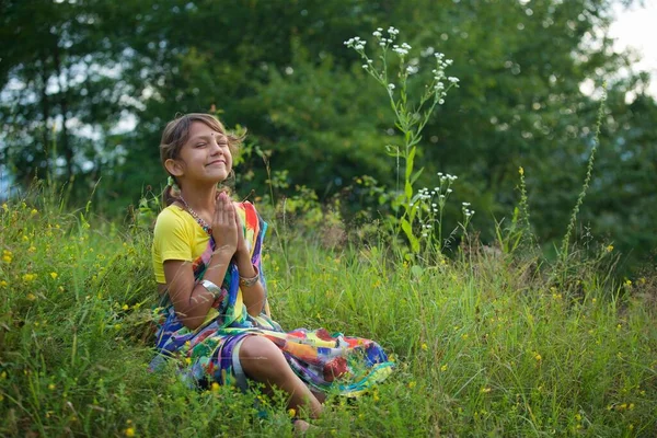 カラフルなサリの女の子はヨガのアーサナの花の牧草地に座って瞑想 — ストック写真