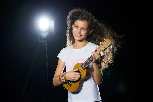 Küçük gitarlı, çekici, kıvırcık bir müzisyenin portresi. Bir müzisyenin kariyeri ve genç yetenekleri kavramı