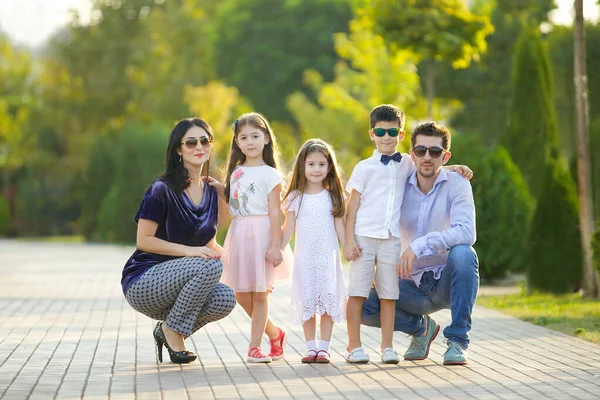 Büyük mutlu bir aile, anne, baba ve üç çocuk kız ve bir oğlan. Ebeveynler çömeldi ve çocuklar bir arada durdular..