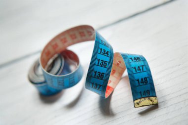 Beyaz ahşap yüzeyde dikiş ve yaratıcılık için bir mezura var. Hobi ve el işi kavramı..