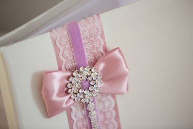 Düğünde yeni evliler için beyaz kapalı dilek kitabı. Masada pembe kurdeleler ve dantellerle süslenmiş..