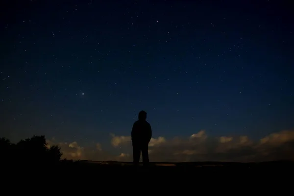 Silhouette of a people against the starry sky at night.