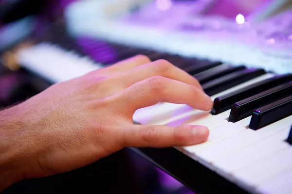 The electronic keyboard musical instrument, the synthesizer and the hands playing it. Close-up of black and white keys. The concept of culture and art.