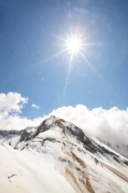 Kış dağı manzarası. Beyaz karla kaplı yüksek dağlar. Dağların üzerinde parlak mavi gökyüzü