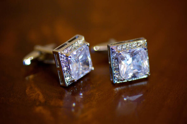 Men's elegant cufflinks with rhinestones lie on the surface of the table.