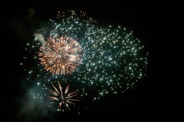 Karanlık gökyüzüne karşı parlak renkli havai fişekler.