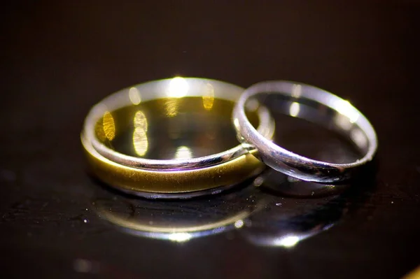 結婚式のための結婚指輪は表面を反映する鏡の上にある 婚約を記念して休日やお祝い — ストック写真