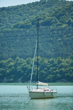 Küçük bir yat açık denizde ya da gölde yüzer. Geminin yelkeni indirildi..