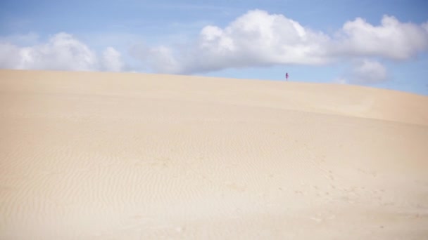 Person, die an der Spitze einer großen Sanddüne entlang geht — Stockvideo