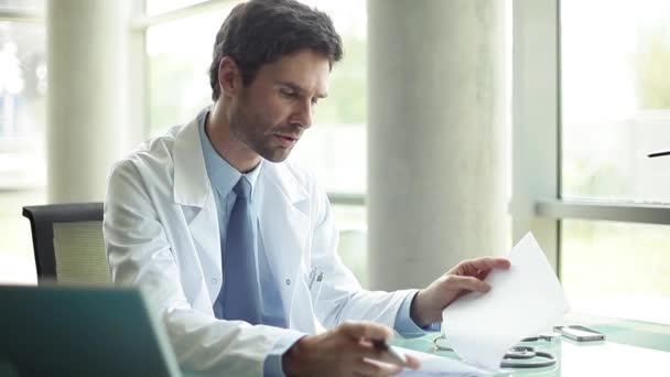 Doctor talking with out-of-frame patient in office — Stock Video