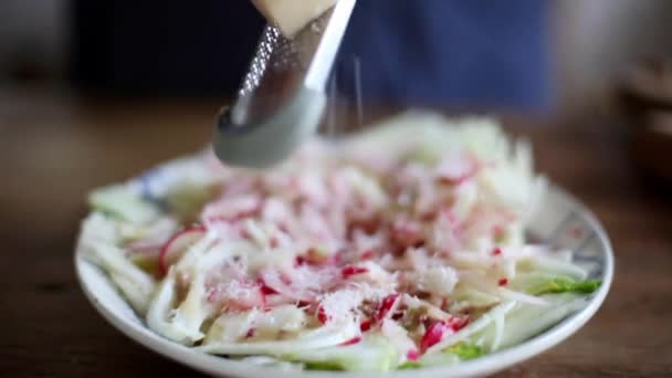 Vrouw raspen kaas over salade — Stockvideo