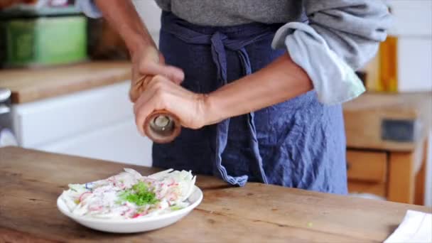 Mujer moliendo pimienta sobre ensalada — Vídeo de stock