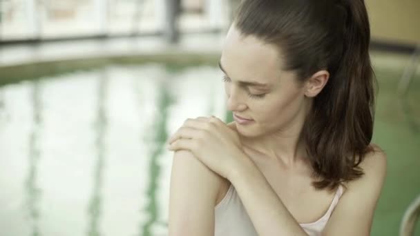 Молодая женщина наносит увлажняющий крем на плечо — стоковое видео
