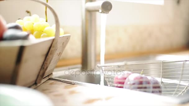 Женщина моет фрукты в раковине — стоковое видео