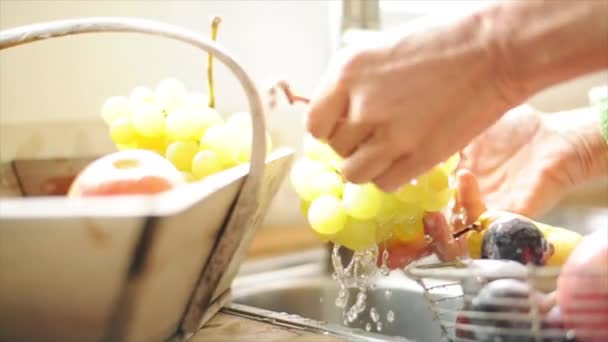 Woman washing grapes at kitchen sink — Stock Video