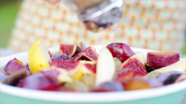 Mujer agitando condimentos sobre frutas cortadas — Vídeos de Stock