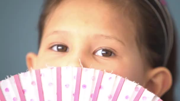 Little girl peeking over top of fan — Stock Video