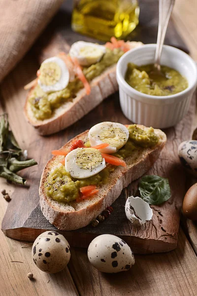 Sliced bread with pea cream and quail eggs — Stock Photo, Image