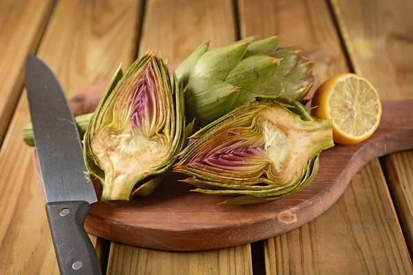 Carciofi tagliati con limone sul tavolo di legno — Foto Stock