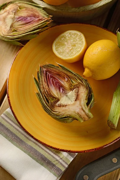 Artichokes cut with lemon on the wooden table — Stock Photo, Image
