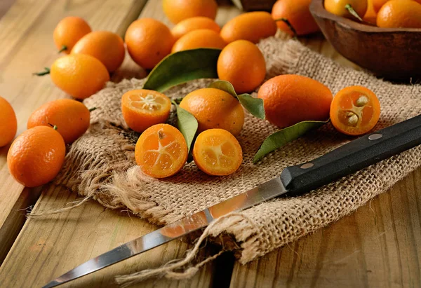 Kumquat auf Jutescreme über dem Holztisch — Stockfoto