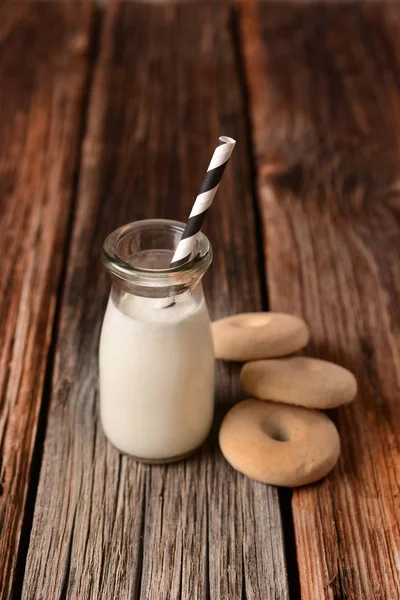 Mjölk i glasflaska med cookies runt — Stockfoto