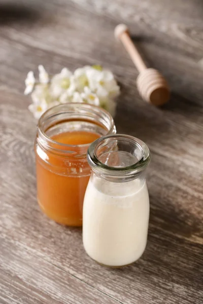 Leche y miel sobre mesa de madera —  Fotos de Stock