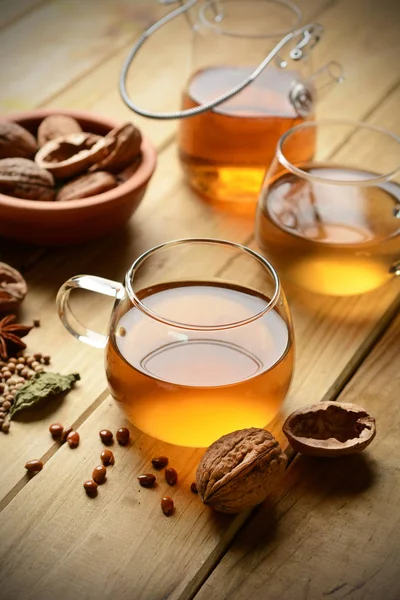 Herbal tea with walnuts and ingredients around — Stock Photo, Image